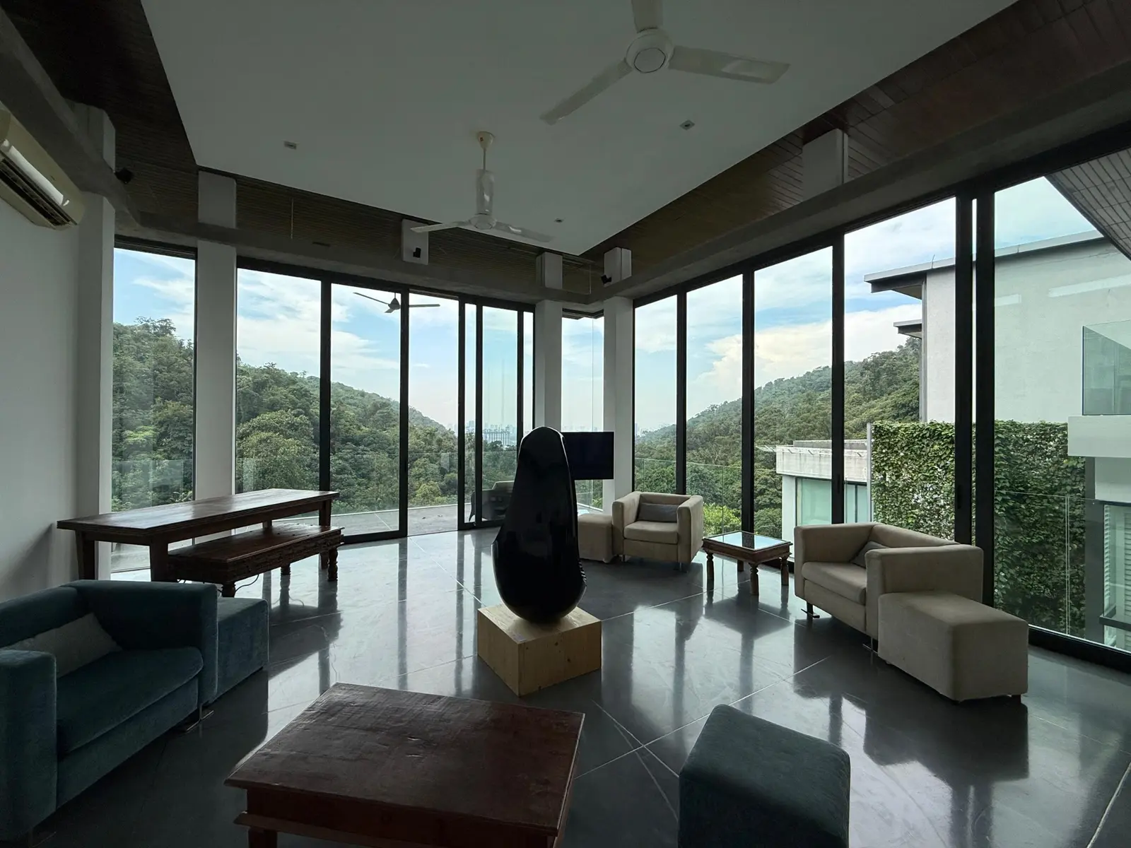 Fully furnished glass-walled living room with green views